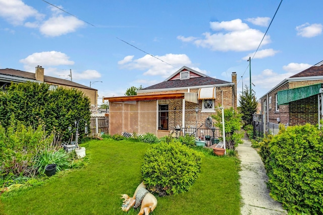 view of front of home with brick siding, fence, a chimney, and a front yard