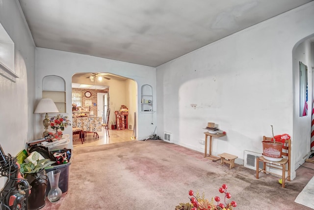 interior space featuring arched walkways, ceiling fan, carpet flooring, and visible vents