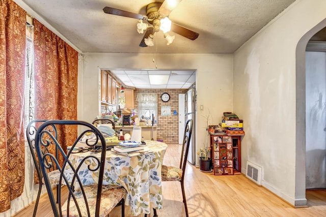 dining room with visible vents, arched walkways, light wood-style floors, and ceiling fan