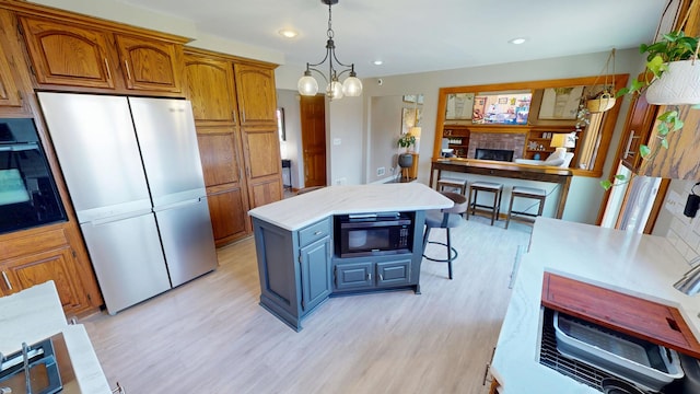 kitchen featuring freestanding refrigerator, black oven, brown cabinets, light wood finished floors, and built in microwave