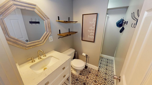 bathroom with toilet, vanity, and baseboards