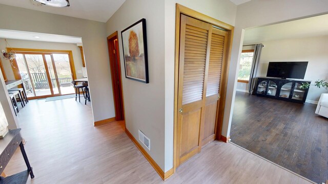 hall with visible vents, baseboards, and wood finished floors