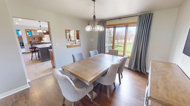 dining room with baseboards, an inviting chandelier, and wood finished floors