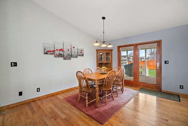 dining area featuring baseboards, lofted ceiling, and light wood-type flooring