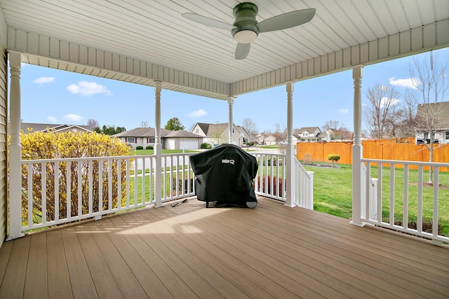 wooden terrace featuring a grill, a yard, a ceiling fan, and a residential view
