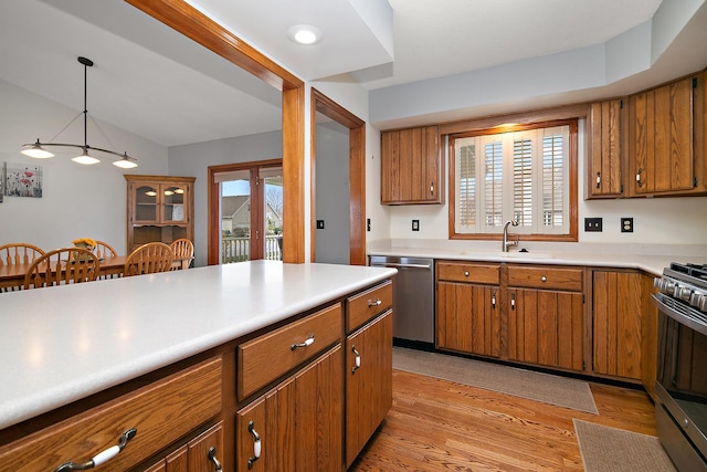 kitchen with light wood-style flooring, a sink, brown cabinets, and appliances with stainless steel finishes