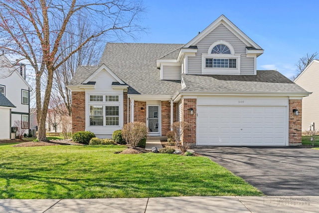 view of front of house featuring a shingled roof, aphalt driveway, a front yard, and brick siding