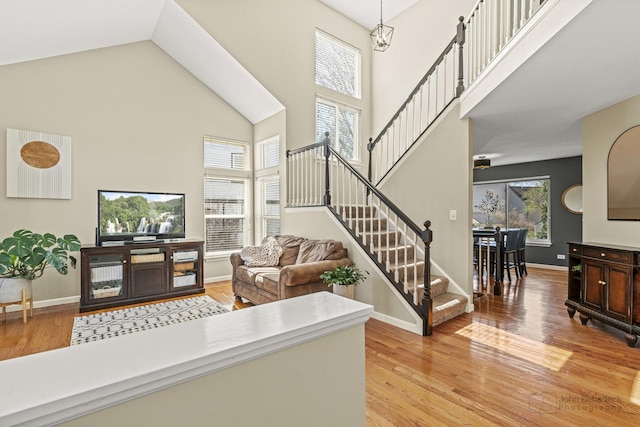 entrance foyer featuring light wood-style floors, a healthy amount of sunlight, a towering ceiling, and stairway