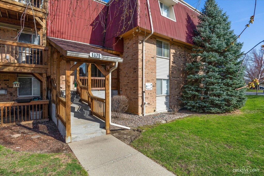 1875 Tall Oaks Dr Unit 2408, Aurora, IL 60505 - doorway to property featuring a lawn and brick siding