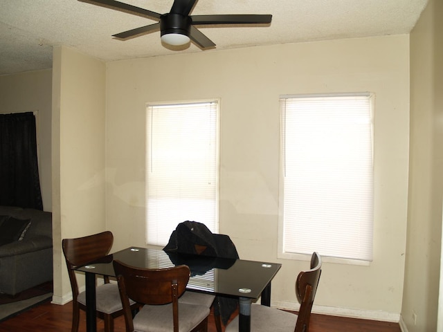 dining space with baseboards, dark wood-style flooring, ceiling fan, and a textured ceiling