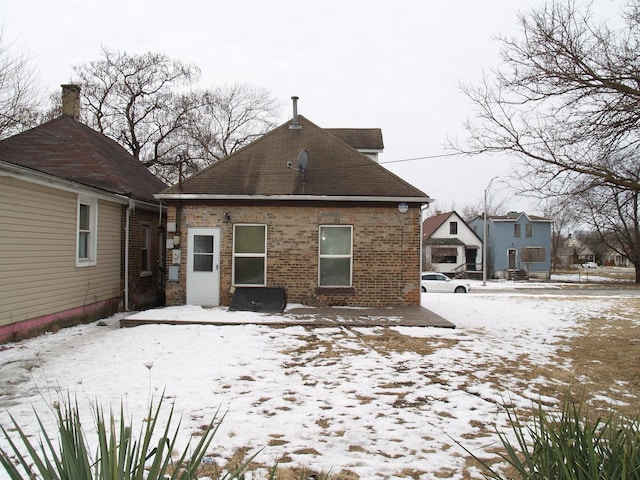 snow covered back of property with brick siding