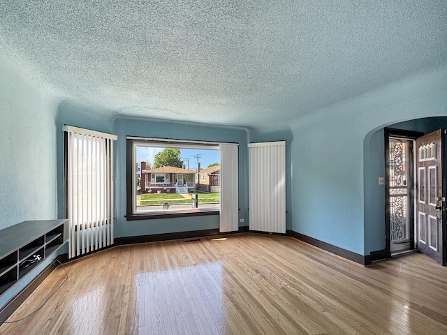 608 W 107th St, Chicago, IL 60628 - unfurnished living room with arched walkways, wood finished floors, a textured ceiling, and baseboards