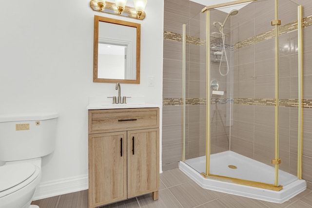 bathroom featuring toilet, a stall shower, vanity, and baseboards