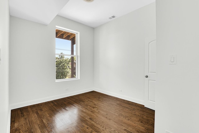 empty room featuring baseboards, dark wood-style floors, and visible vents
