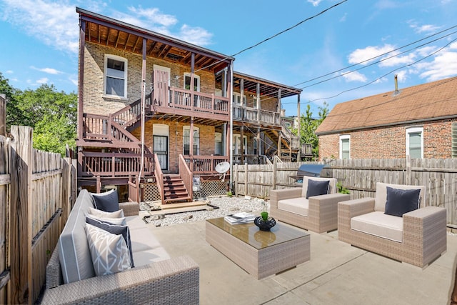 rear view of property with a fenced backyard, an outdoor living space, a patio, and stairs