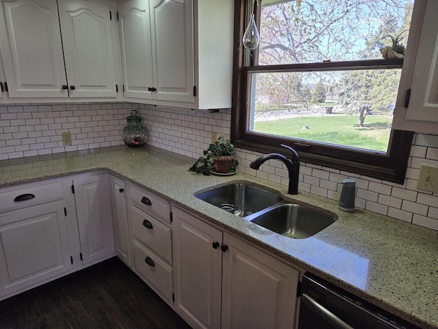 kitchen featuring a sink, backsplash, stainless steel dishwasher, and white cabinets