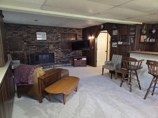 living room with brick wall, a bar, a fireplace, wooden walls, and carpet flooring