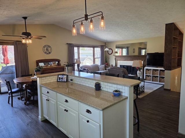 kitchen with open floor plan, a textured ceiling, and vaulted ceiling