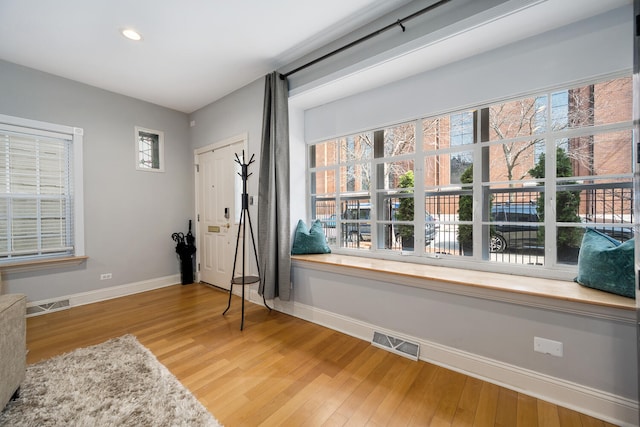 sitting room with baseboards, visible vents, and light wood finished floors
