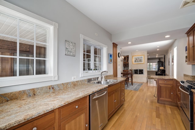 kitchen with light wood-type flooring, a sink, visible vents, appliances with stainless steel finishes, and brown cabinets