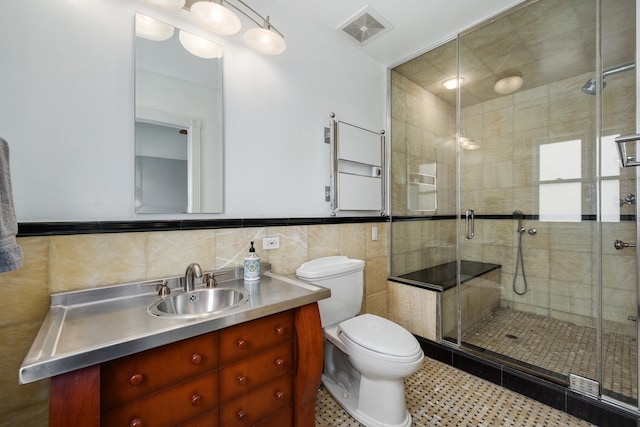 bathroom featuring toilet, vanity, a shower stall, visible vents, and tile walls