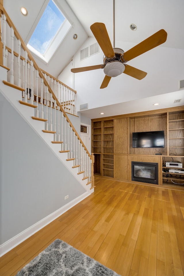 living room featuring hardwood / wood-style floors, a skylight, built in shelves, and visible vents