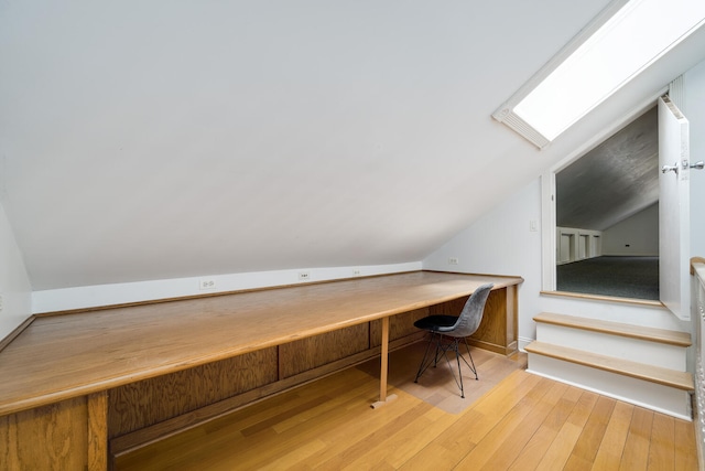 unfurnished office with lofted ceiling with skylight and hardwood / wood-style floors