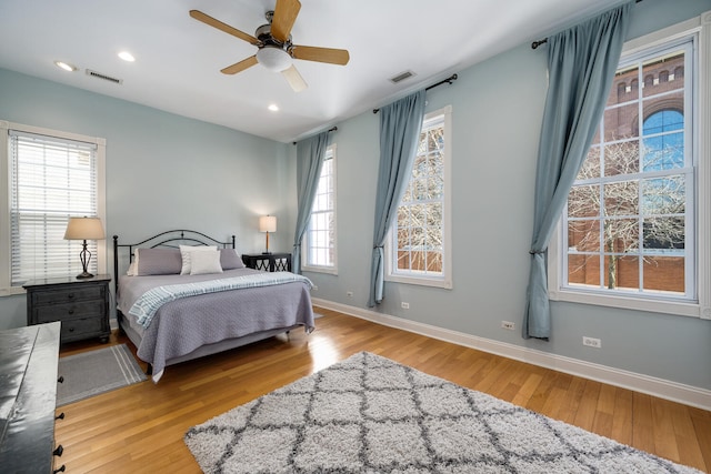 bedroom with wood finished floors, recessed lighting, baseboards, and visible vents
