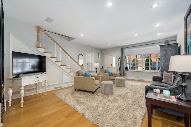 living room featuring light wood finished floors, visible vents, recessed lighting, and stairway