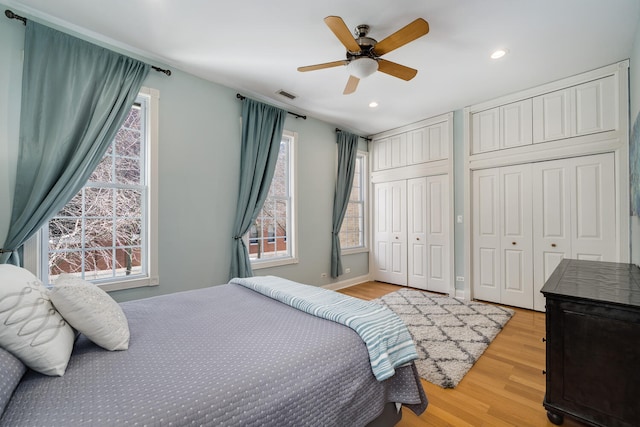 bedroom featuring recessed lighting, multiple closets, multiple windows, and light wood-style floors