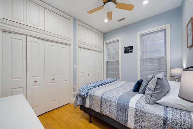 bedroom with recessed lighting, multiple closets, light wood finished floors, visible vents, and a ceiling fan