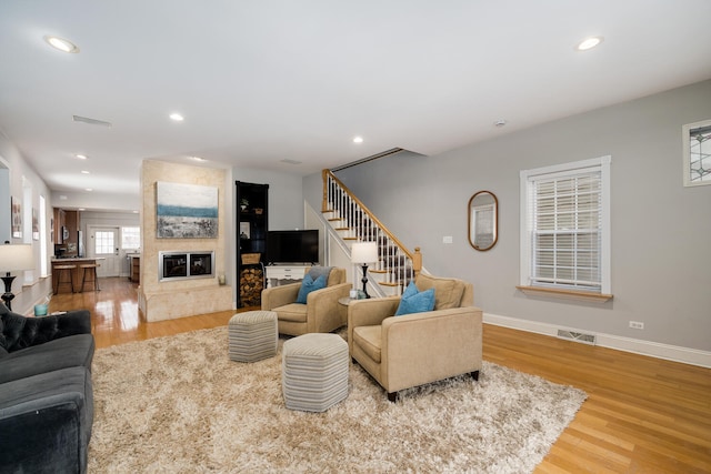 living room featuring visible vents, baseboards, stairs, wood finished floors, and recessed lighting