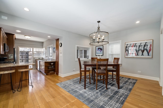dining space featuring an inviting chandelier, baseboards, and light wood finished floors