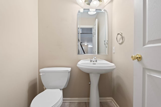 bathroom featuring toilet, baseboards, tile patterned flooring, and a sink