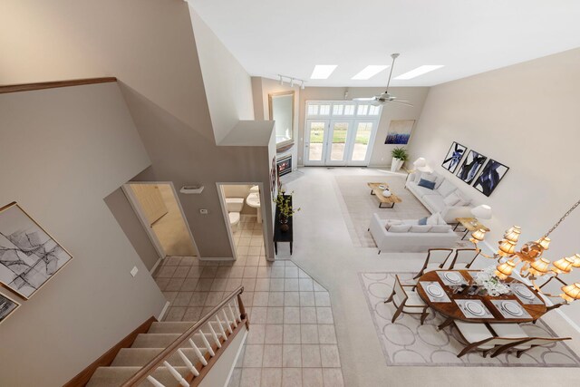 living room featuring tile patterned floors, a skylight, a ceiling fan, and baseboards
