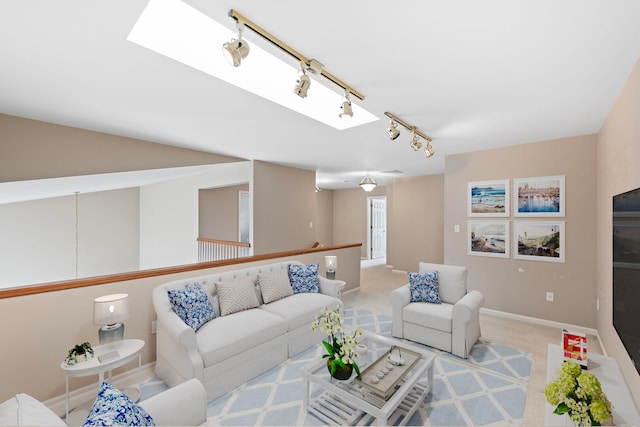 carpeted living room featuring a skylight, baseboards, and track lighting