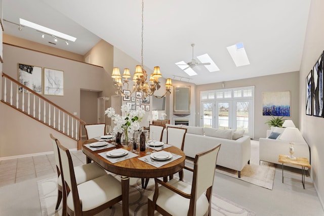dining space featuring baseboards, a chandelier, stairway, a skylight, and high vaulted ceiling