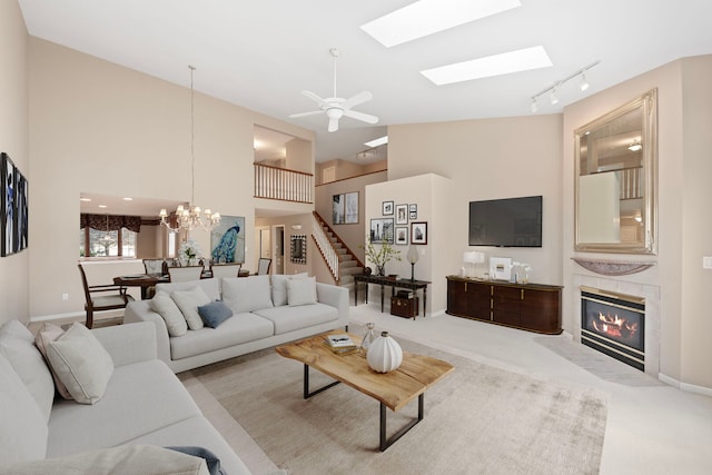 living room with rail lighting, a tile fireplace, ceiling fan with notable chandelier, and carpet floors