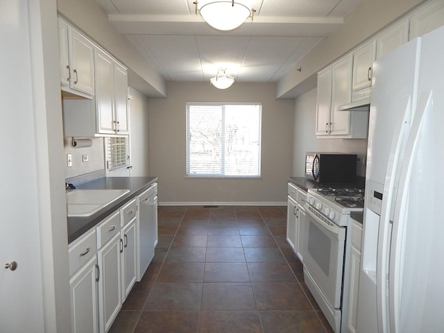 kitchen featuring white appliances, dark countertops, a sink, and white cabinetry