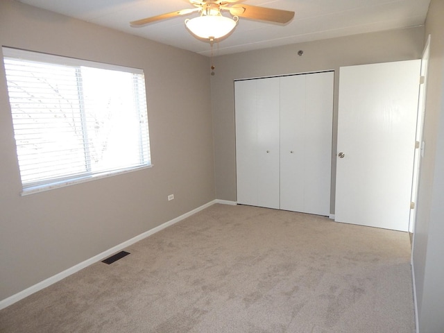 unfurnished bedroom featuring a closet, carpet flooring, a ceiling fan, baseboards, and visible vents