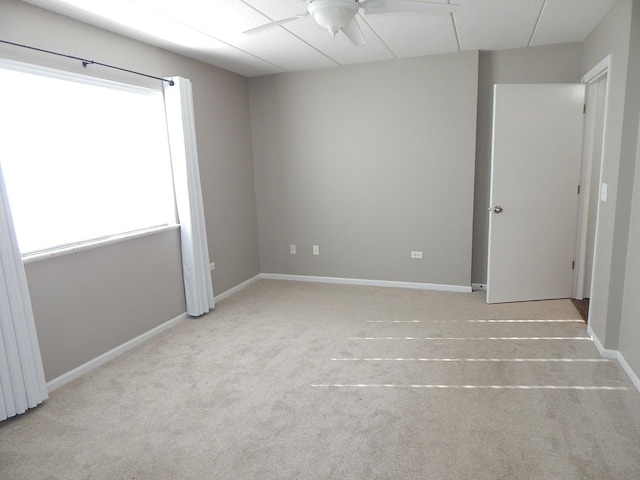 spare room with baseboards, ceiling fan, and carpet