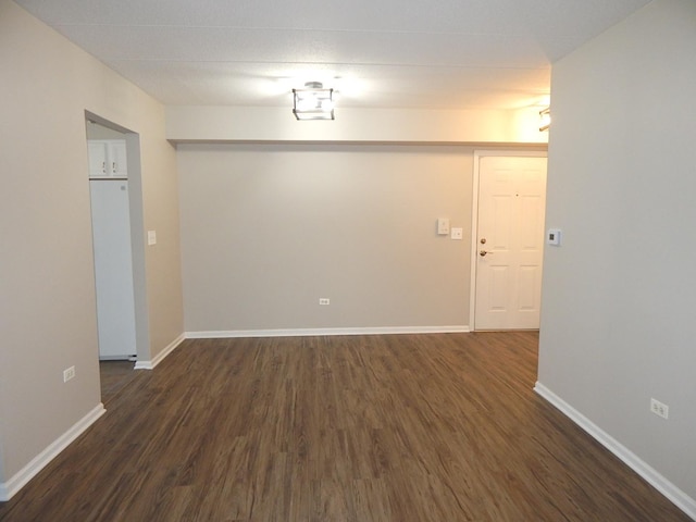 spare room with dark wood-style floors and baseboards