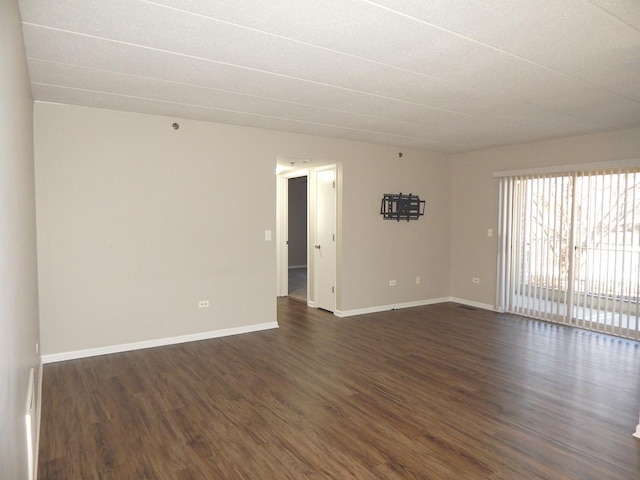 unfurnished room with baseboards and dark wood-style flooring