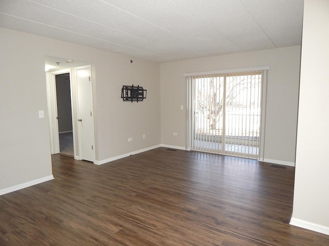 empty room featuring baseboards and dark wood finished floors