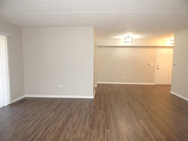 unfurnished room featuring baseboards and dark wood-style flooring