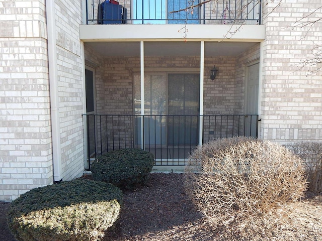 doorway to property featuring a balcony and brick siding