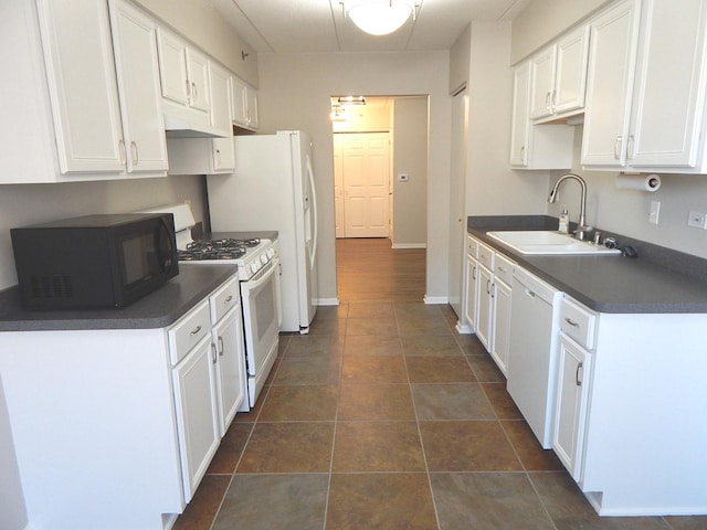 kitchen featuring white appliances, dark countertops, a sink, and white cabinetry