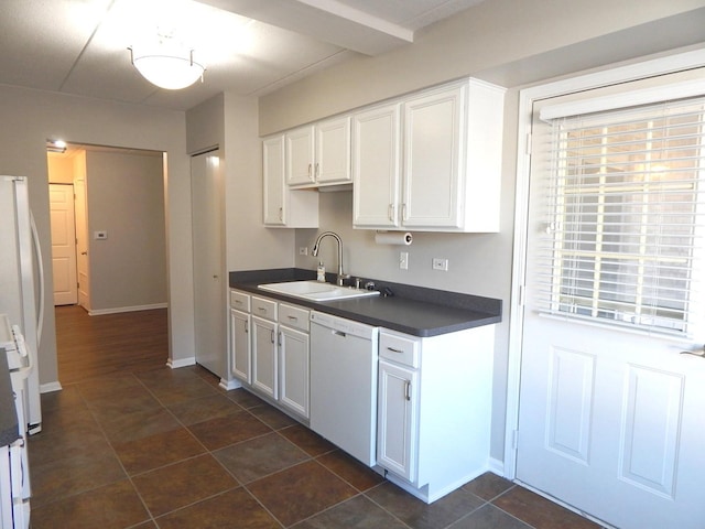 kitchen featuring white cabinetry, white appliances, baseboards, a sink, and dark countertops