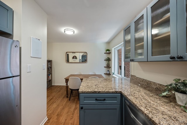 849 W Buckingham Pl Unit G, Chicago, IL 60657 - kitchen with appliances with stainless steel finishes, light stone countertops, light wood finished floors, a peninsula, and glass insert cabinets
