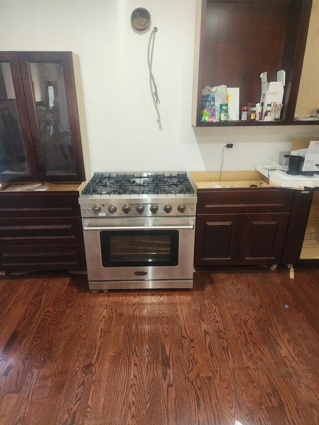 kitchen with high end stainless steel range, light countertops, dark wood-style floors, and dark brown cabinetry